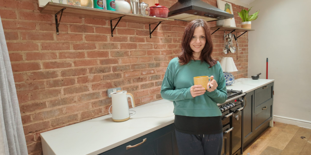 Rachel Thompson, physiotherapist, relaxing at home with a cup of coffee in her kitchen